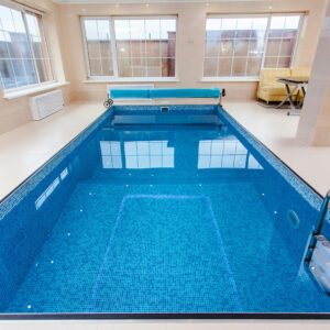Bright indoor swimming pool with luxury seating and large windows.