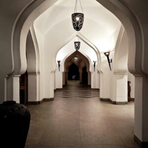 Elegant corridor with arches and hanging lamps in Hampi, India, showcasing stunning architecture.